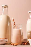 Various non dairy vegan plant milk and ingredients on pink background photo