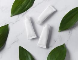 White tubes of cream on a marble background photo