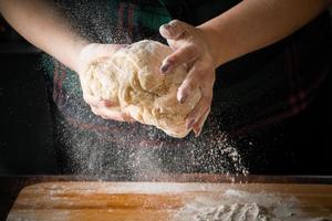 Chef kneads pizza dough on a board photo