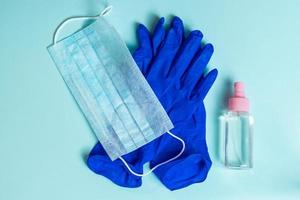 guantes de látex, mascarilla médica y antiséptico sobre un fondo azul foto