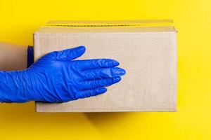 A man in latex gloves delivers a parcel on yellow background photo