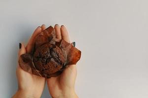 Vista superior del muffin de chocolate en manos de mujer foto