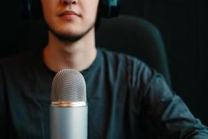 El hombre está transmitiendo al aire en un altavoz en un estudio de podcast con micrófono