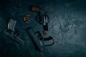 Tres pistolas y balas en el cuadro negro. foto