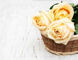 canasta con rosas en una vieja mesa de madera foto