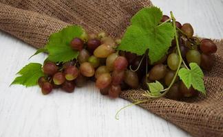 Grapes with leaves on an old wooden background photo