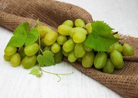 Grapes with leaves on an old wooden background photo