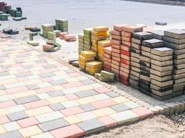 Stack of colorful square new bricks in process of laying for pedestrian pathway photo