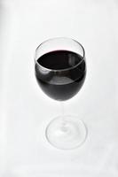 Gran vaso de vino tinto sobre un fondo blanco. foto