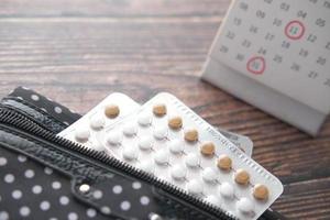 Birth control pills on wooden background, close up photo