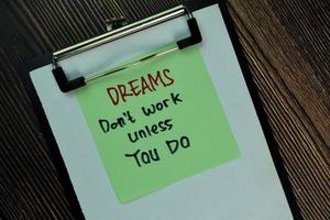 Dreams don't work unless you do written on sticky notes isolated on wooden table photo