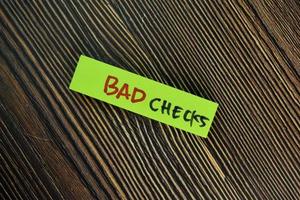 Bad checks written on sticky notes isolated on wooden table photo