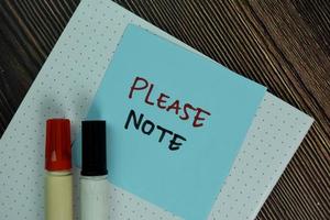 Please note written on sticky notes isolated on wooden table