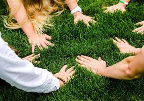 Circle of people with hands on grass photo