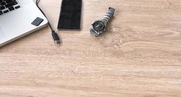 reloj, teléfono móvil y computadora portátil en una mesa foto