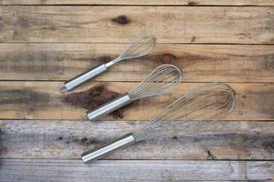 3 whisk different size on wood table photo