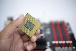 Hand holding a CPU and a motherboard socket for a CPU isolated on white background photo