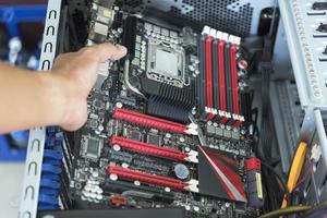 mano agarrando una placa base con una cpu para una caja de computadora atx foto