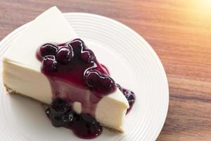 Tarta de queso con crema de arándanos en una placa blanca sobre una mesa de madera foto