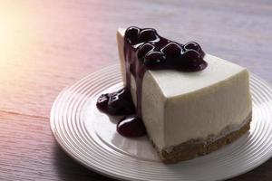 Blueberry cream cheesecake on a white plate on a wooden table photo