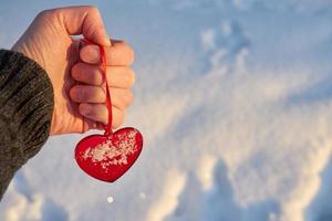 corazón rojo en la mano con nieve foto