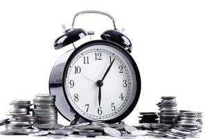 Black alarm clock and stack of coins photo