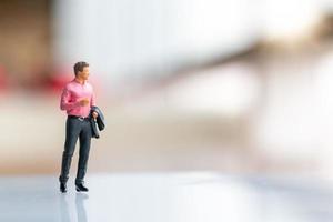 Miniature businessman standing on empty space for text photo