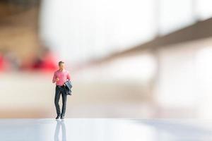 Miniature businessman standing on empty space for text photo