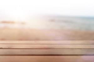 El enfoque selectivo de la mesa de madera vieja con desenfoque de fondo de playa hermosa para mostrar foto