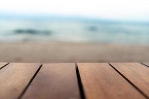 El enfoque selectivo de la mesa de madera vieja con desenfoque de fondo de playa hermosa para mostrar foto