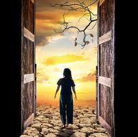 Composite of woman walking through open doors into sunset photo