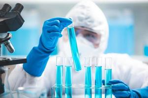 Scientist looking at test tubes photo