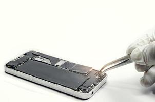 Close up of a professional technician repairing a camera phone with mini tools on a desk photo