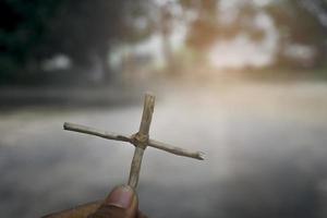 mano sosteniendo una cruz de Jesucristo en una tumba. símbolo de la creencia en el cristianismo religión foto