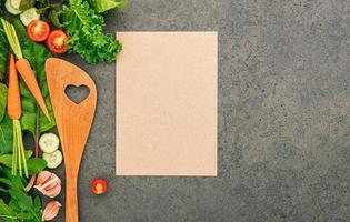 Wooden spatula and vegetables on a dark stone background. Healthy food and cooking concept. photo