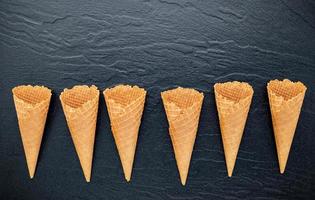 Lay Flat de conos de helado sobre un fondo de piedra oscura, cono de helado crujiente con espacio de copia para el diseño del menú de dulces foto