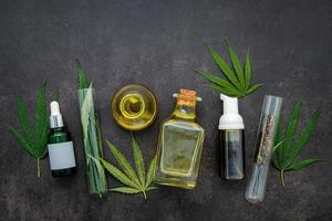 Glass bottles of hemp oil and hemp leaves set up on a concrete background photo