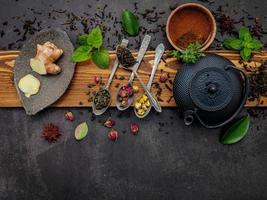 Black cast iron tea pot with herbal tea set up on a dark stone background photo
