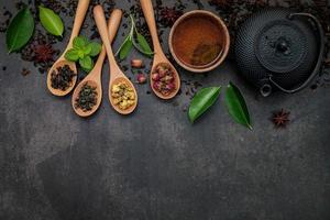 Black cast iron tea pot with herbal tea set up on a dark stone background photo