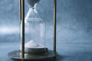 Sand flowing through hourglass on table photo