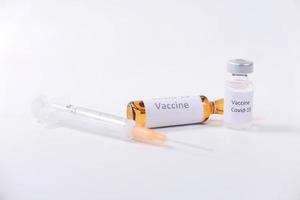 Close up of coronavirus vaccine and syringe on white background photo