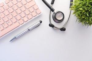 Pen, keyboard, and stethoscope on white desk photo