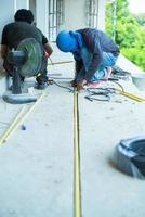 Workers installing the electrical wire and pipe in the house under construction photo