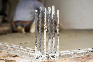 Selective focus on the reinforcement steel in the cement floor at the construction site with blurred worker in background photo