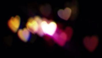 Realistic colorful light bokeh heart shape on black background. video