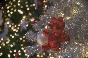 Abstract background of glittering bokeh lights with blurred ornament on the silver Christmas tree in foreground photo