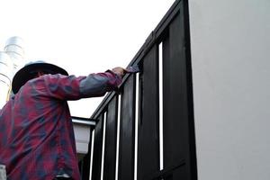 Motion blurred hand of worker painting black color on the steel fence photo