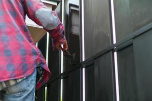 Motion blurred hand of worker painting black color on the steel fence photo