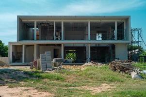 El paisaje y la perspectiva de la casa en construcción con montones de materiales y equipos con el cielo azul claro en segundo plano. foto