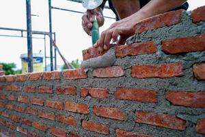 Primer plano de las manos del trabajador instalando los albañiles para la construcción de la pared en el sitio de construcción. foto